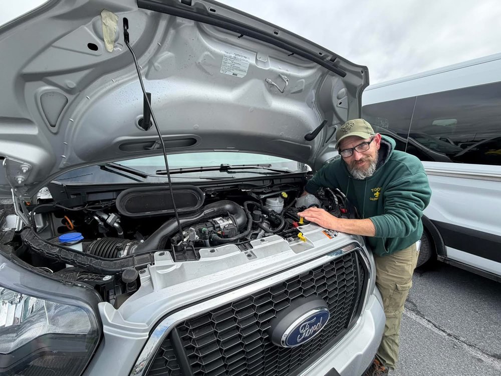 Scoutmaster Brian helping fix a stranded family's van on the side of the road