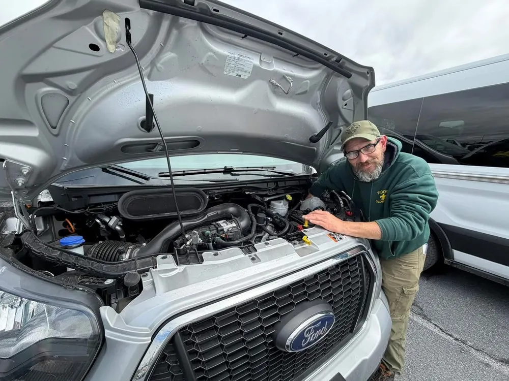 Scoutmaster Brian helping fix a stranded family's van on the side of the road